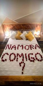 Una cama con pétalos de rosa que deletrea la palabra "felices". en PENEDO ACONCHEGO LOFT: VISTA, CONFORTO E NATUREZA!, en Penedo