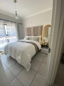 a white bedroom with a bed and a mirror at One Bedroom The Blyde in Pretoria