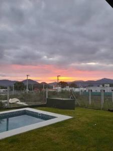 einen Pool im Garten mit Sonnenuntergang im Hintergrund in der Unterkunft Yunka House, Salta in Vaqueros