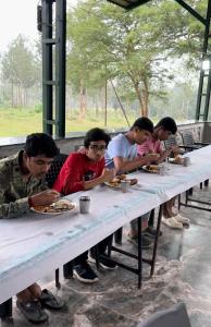 a group of young men sitting at a table eating food at Singaras Coffee Country in Masinagudi