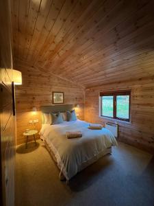 a bedroom with a large bed in a wooden cabin at Mallard Lodge - Arscott Lodges in Shrewsbury
