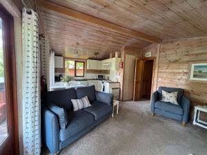 a living room with a blue couch and a kitchen at Mallard Lodge - Arscott Lodges in Shrewsbury