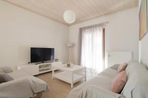 sala de estar blanca con sofá y TV en House Belelis, en Afionas