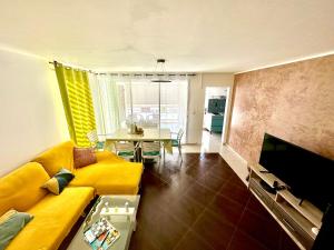 ein Wohnzimmer mit einem gelben Sofa und einem Tisch in der Unterkunft T3 agréable au Gosier à proximité de la plage in Le Gosier