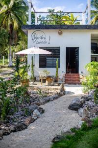 a white house with an umbrella and a patio at Bleibe- Quédate! in Bacalar