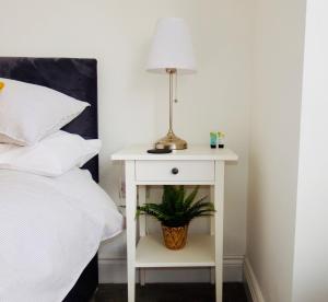 a white bedside table with a lamp and a plant at Newly Renovated 3 Bedroom Victorian Detached House in Bournemouth