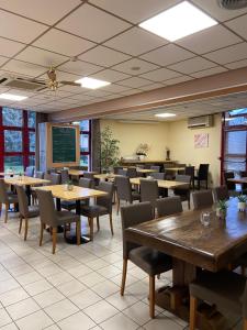 une salle à manger avec des tables, des chaises et un tableau noir dans l'établissement Hôtel Mélodie, à Bellignat