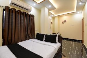 OYO Chilli Pepper Hotel and Restaurant في kolkata: غرفة نوم بسرير ذو شراشف بيضاء ومخدات سوداء