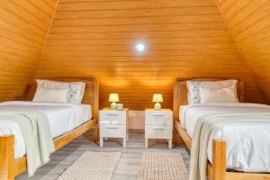 two beds in a room with wooden walls at Atlantic View, a Home in Madeira in Ponta do Sol