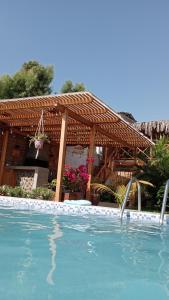 a swimming pool in front of a wooden pergola at Costa Luna in Vichayito