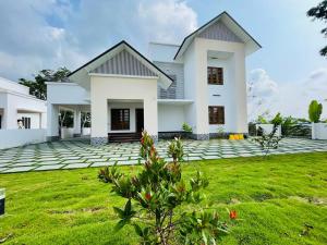 a white house with a green yard at Highrange Villas in Vagamon