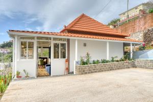 a small white house with a red roof at Atlantic View, a Home in Madeira in Ponta do Sol