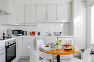una cucina bianca con tavolo in legno e armadietti bianchi di #7 six sleeps Zone1 - BrickLane a Londra
