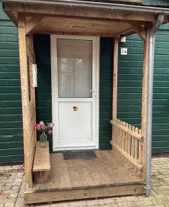 eine weiße Tür in einem grünen Haus mit einer Veranda in der Unterkunft De Heijense Molen Retro Camping in Heijen