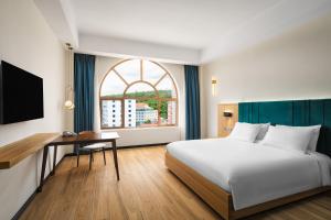 1 dormitorio con cama, escritorio y ventana en Grand Pailin Casino & Resort, 