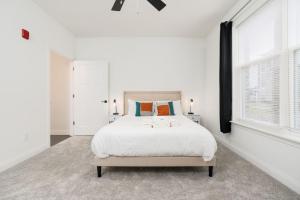 a white bedroom with a large bed and windows at Corporate Housing by MGM in Whitestown