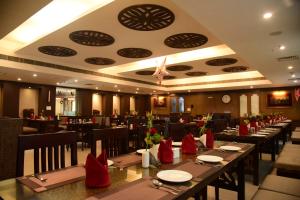 un comedor con mesas largas y sillas rojas en Hotel Bishnu Palace, en Jhārsuguda