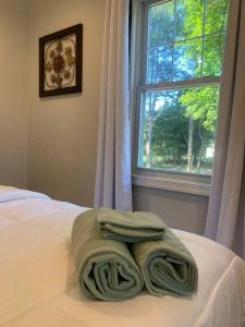 a green towel laying on a bed in front of a window at Serene Lush 2BR Gem, on 1 acre Silver Spring in Silver Spring
