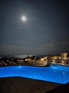a large blue swimming pool at night with the moon at Summer Senses Luxury Resort in Logaras