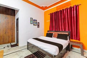 OYO Flagship Drip Stay Inn في لاكناو: غرفة نوم بسرير ونافذة حمراء