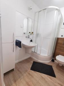 een witte badkamer met een wastafel en een douche bij Apartamenty Pszczew Krzysztof Michna Lubuskie Mazury Apartament "Natalia" in Pszczew