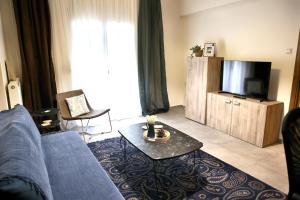 een woonkamer met een blauwe bank en een tv bij Στυλ & άνεση στο κέντρο La Maison 12 Ανακαινισμένο διαμέρισμα in Larisa