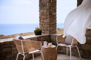 a patio with two chairs and a table and a window at Summer Senses Luxury Resort in Logaras