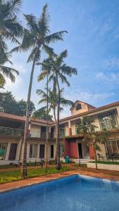 a building with palm trees in front of a swimming pool at Royal Breeze Resort in Alibag