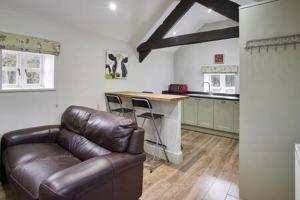 a living room with a leather couch and a kitchen at Host & Stay - Cote in Consett