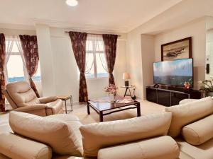 Il comprend un salon avec des canapés et une télévision à écran plat. dans l'établissement Penthouse Aloha Tower Near Danga Bay@ 8-10Pax, à Johor Bahru