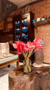 Morro Azul Chalés في تيمبو: مزهرية مليئة بالورود الحمراء على طاولة
