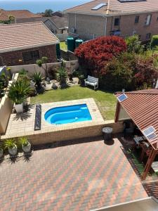 a swimming pool in a yard next to a house at Chardonnay Holiday Apartment in Jeffreys Bay