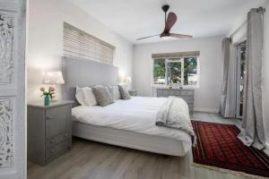 a white bedroom with a bed and a ceiling fan at Onrus Cottage in Hermanus