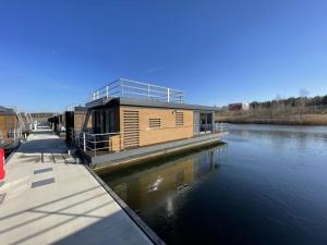 a wooden house on the side of a river at Hausboot Dicke Bärta in Klitten