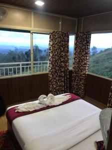 a bed in a room with two windows at Nature Dale Munnar in Munnar