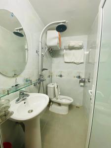 a bathroom with a sink and a toilet and a mirror at HOTEL HOÀNG LONG in Diện Biên Phủ