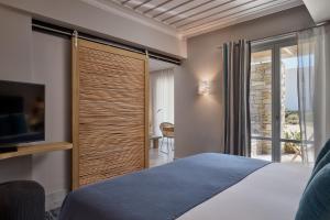 a bedroom with a bed and a tv and a window at Summer Senses Luxury Resort in Logaras