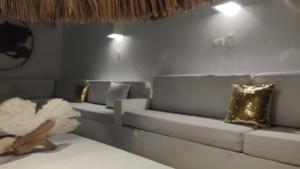 una sala de estar con un sofá blanco con almohadas de oro en Rincón del mar Hotel Boutique los Veleros, en San Onofre
