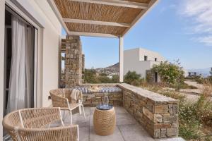 a patio with chairs and a table on a stone wall at Summer Senses Luxury Resort in Logaras