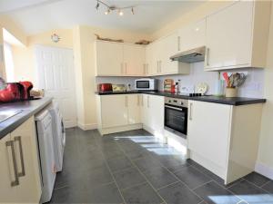 a kitchen with white cabinets and a tile floor at 2 bed property in Gower 78344 in Reynoldston