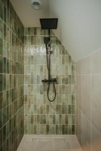 a shower in a bathroom with green tiles at SkyGlamp in Ustroń