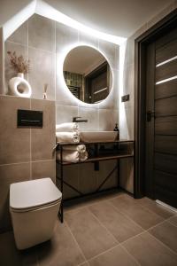 een badkamer met een wastafel, een toilet en een spiegel bij SkyGlamp in Ustroń