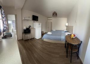 ein Schlafzimmer mit einem Bett und einem Tisch sowie eine Küche in der Unterkunft Garden Square Inn in Markopoulo