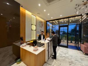 zwei Männer stehen an einem Tresen in einer Lobby in der Unterkunft Hotel Three Seasons in Vrindāvan