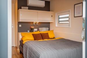 Un dormitorio con una cama con almohadas amarillas y una ventana en Hausboot Skyline en Klitten