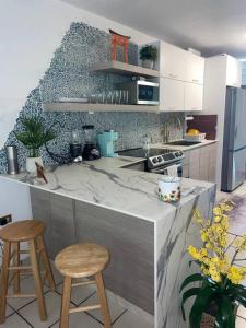 eine Küche mit einer Theke und 2 Hockern in einer Küche in der Unterkunft *NEW CampoMar Beachfront 2Bdrm Villa in Arroyo in Arroyo