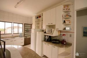 a kitchen with white cabinets and a white refrigerator at Cobertura duplex piscina churras e 2 vagas super arejado in Mongaguá