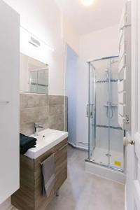 ein Bad mit einem Waschbecken und einer Glasdusche in der Unterkunft Cocon proche Disneyland Paris (15 mn) in Thorigny-sur-Marne