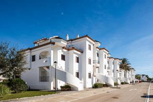 a white building with balconies on a street at Apartamento familiar muy soleado cerca de la playa y parking incluido in Chiclana de la Frontera