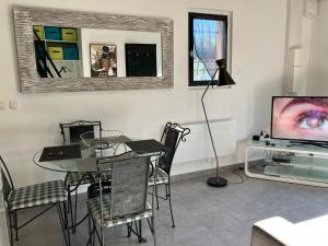 ein Esszimmer mit einem Tisch und einem TV in der Unterkunft Beau duplex climatisé dans une villa calme. in Peymeinade